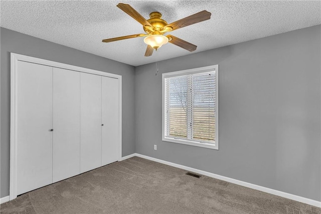 unfurnished bedroom featuring a ceiling fan, a textured ceiling, a closet, carpet, and baseboards