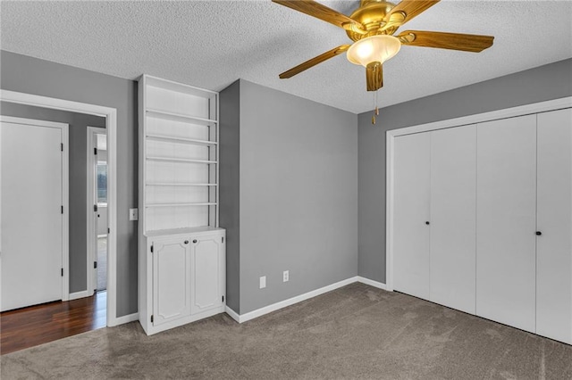 unfurnished bedroom featuring a closet, carpet floors, a textured ceiling, and baseboards