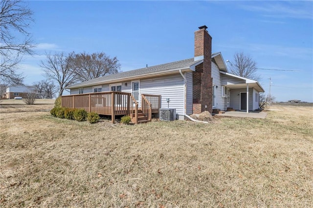 rear view of house featuring a deck, a yard, central AC, and a chimney