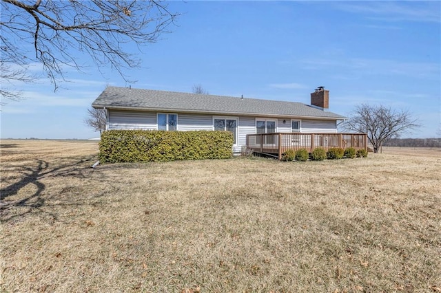 rear view of property with a deck, a chimney, and a yard