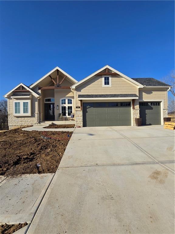 craftsman house featuring an attached garage, stone siding, and driveway