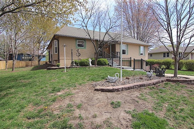 225 N Woodson Dr, Raymore, MO 64083 - rear view of house featuring brick siding, fence, a lawn, and roof with shingles
