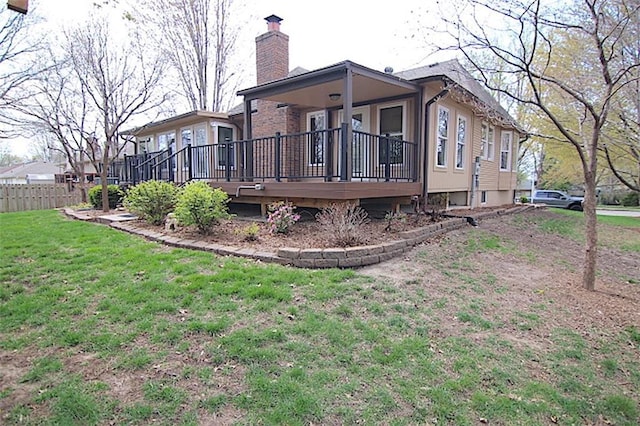 225 N Woodson Dr, Raymore, MO 64083 - rear view of house featuring a yard, fence, and a chimney