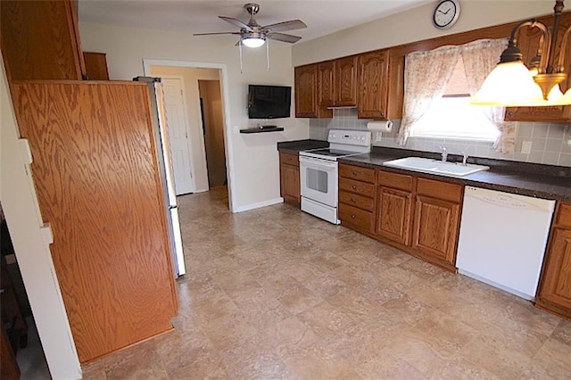 225 N Woodson Dr, Raymore, MO 64083 - kitchen featuring white appliances, a ceiling fan, dark countertops, brown cabinets, and a sink