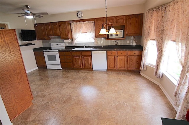 225 N Woodson Dr, Raymore, MO 64083 - kitchen featuring brown cabinetry, tasteful backsplash, white appliances, and a sink