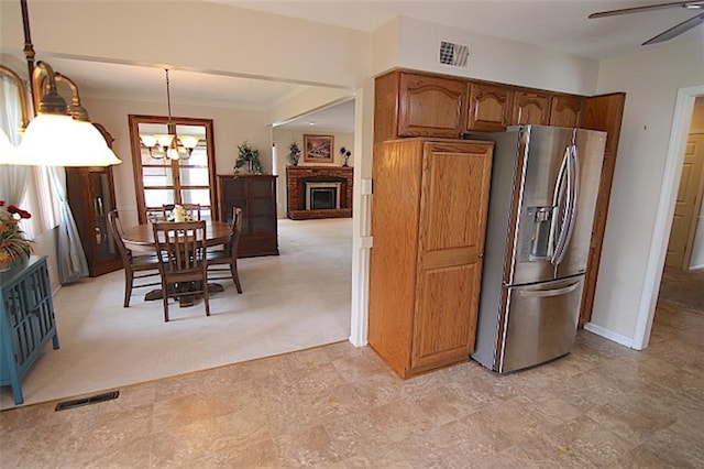 225 N Woodson Dr, Raymore, MO 64083 - kitchen with stainless steel fridge with ice dispenser, brown cabinets, visible vents, and ceiling fan with notable chandelier