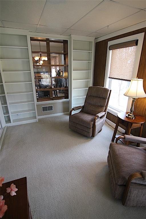 225 N Woodson Dr, Raymore, MO 64083 - living area featuring carpet floors, built in shelves, a chandelier, and visible vents