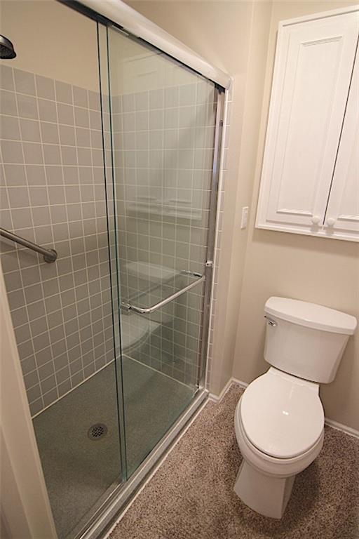 225 N Woodson Dr, Raymore, MO 64083 - bathroom featuring toilet, a shower stall, and baseboards