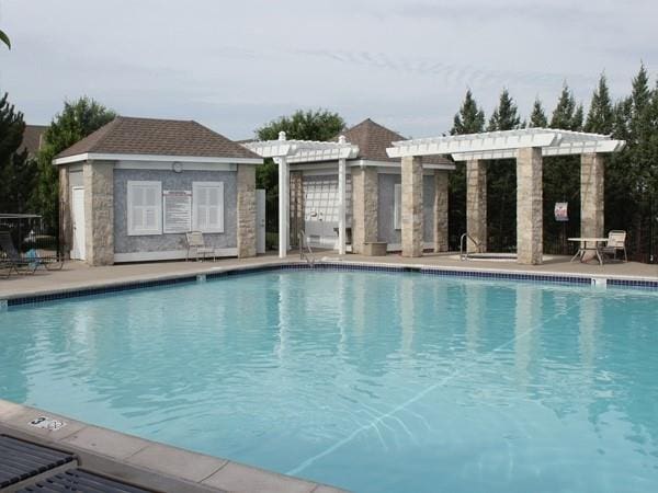 pool with a patio area, a pergola, and an outbuilding