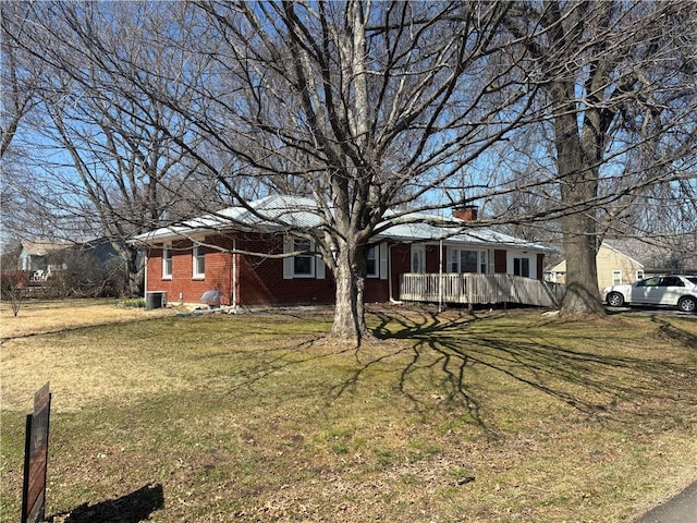 view of front of house with a front yard, central AC unit, and brick siding