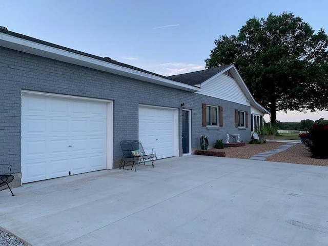 view of side of home featuring concrete driveway and brick siding