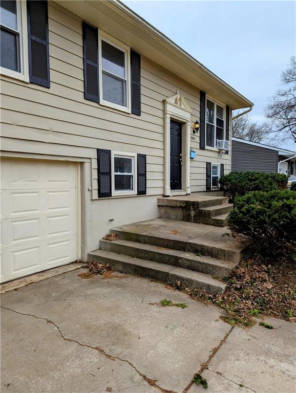 doorway to property with cooling unit, driveway, and a garage