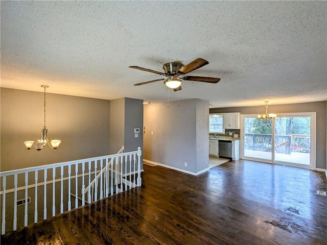 spare room featuring ceiling fan with notable chandelier, a textured ceiling, baseboards, and wood finished floors