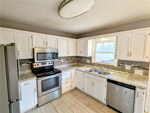 kitchen featuring appliances with stainless steel finishes, white cabinetry, and a sink