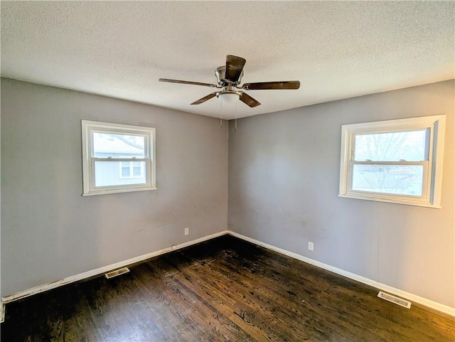 unfurnished room with visible vents, dark wood-style flooring, and baseboards