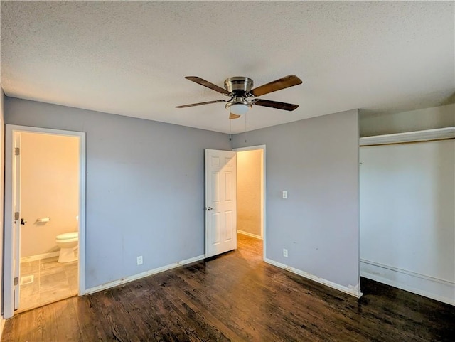 unfurnished bedroom featuring baseboards, ensuite bath, wood finished floors, a closet, and a textured ceiling