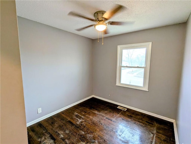 empty room with dark wood finished floors, baseboards, visible vents, and ceiling fan