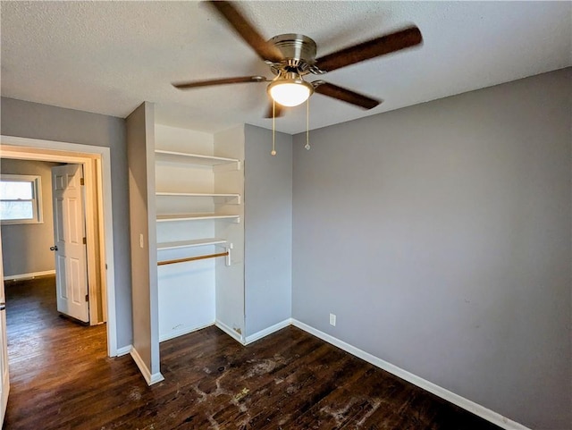 unfurnished bedroom featuring dark wood-type flooring, ceiling fan, baseboards, a closet, and a textured ceiling