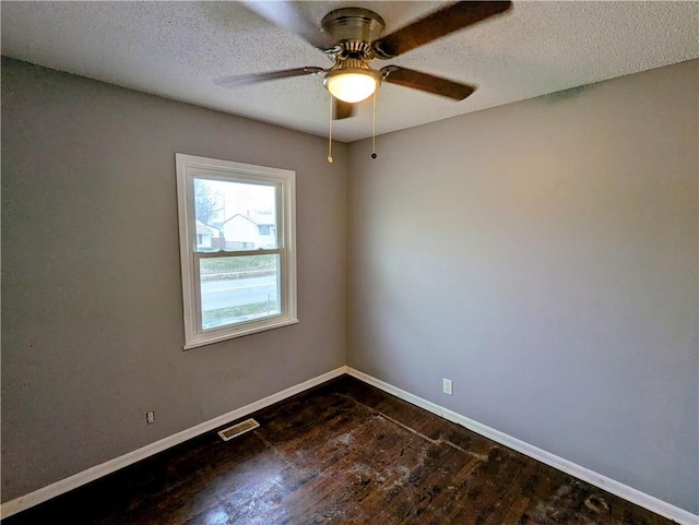 unfurnished room with visible vents, baseboards, dark wood-style flooring, ceiling fan, and a textured ceiling