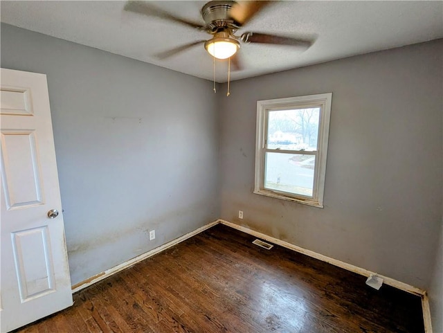 unfurnished room featuring visible vents, baseboards, dark wood-type flooring, and ceiling fan