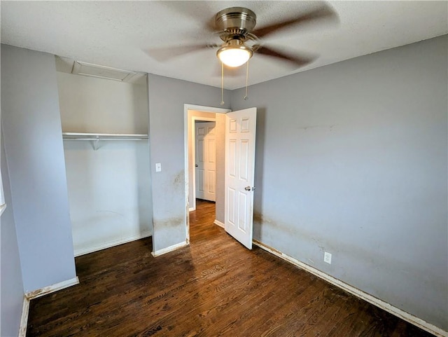 unfurnished bedroom featuring wood finished floors, a closet, baseboards, attic access, and ceiling fan