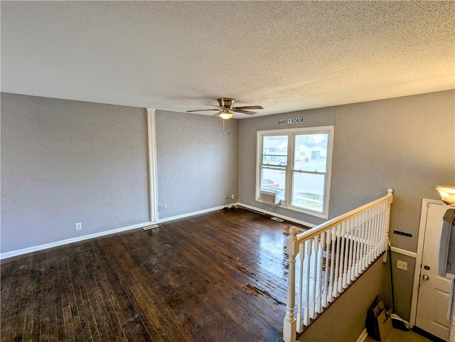 spare room with baseboards, ceiling fan, wood finished floors, a textured wall, and a textured ceiling