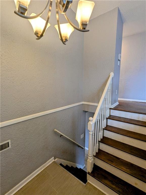 stairway featuring baseboards and a textured wall