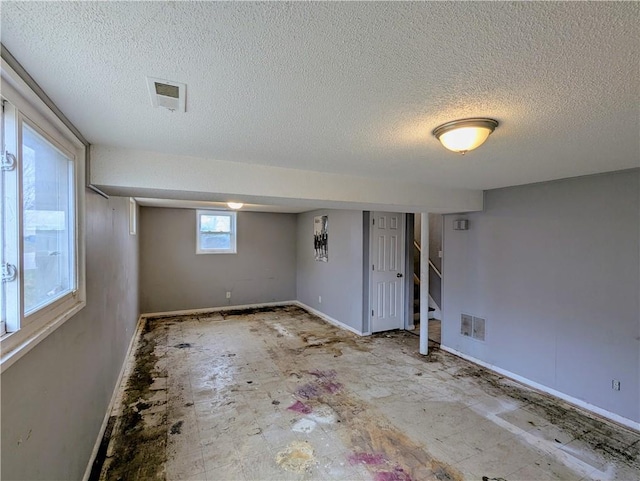 basement featuring stairs, baseboards, and visible vents