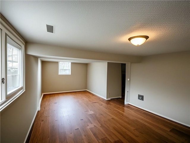 spare room with wood finished floors, baseboards, and a textured ceiling