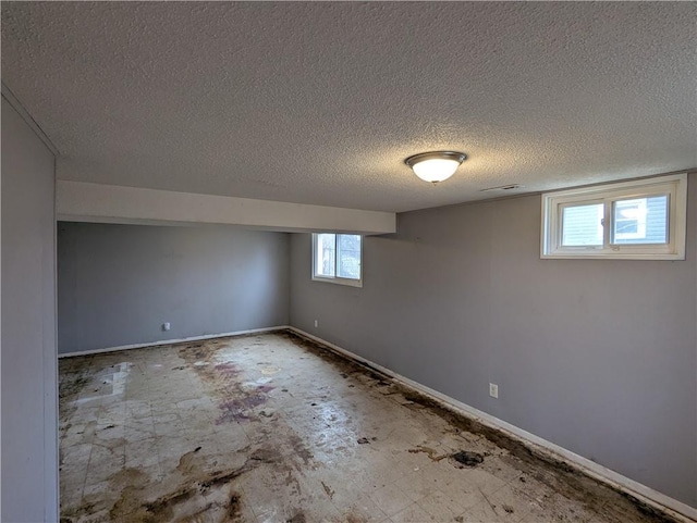 below grade area featuring visible vents, baseboards, and a textured ceiling