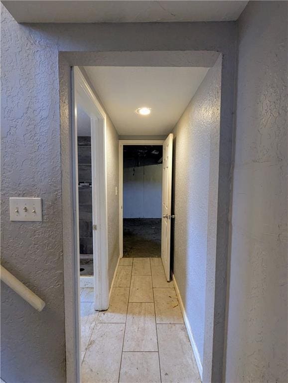 corridor with baseboards and a textured wall