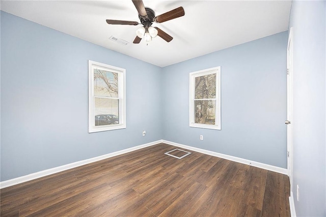 unfurnished room featuring visible vents, a ceiling fan, baseboards, and dark wood-style flooring