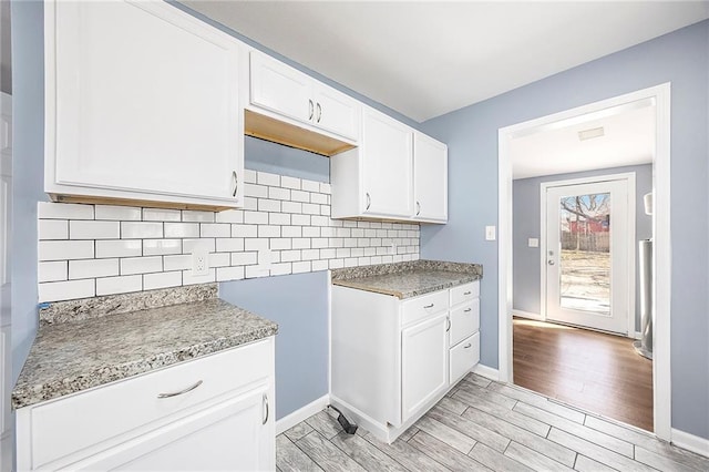 kitchen with light countertops, white cabinets, light wood-style floors, and tasteful backsplash