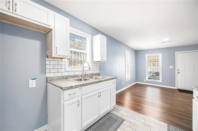 kitchen with wood finished floors, baseboards, a sink, light countertops, and tasteful backsplash