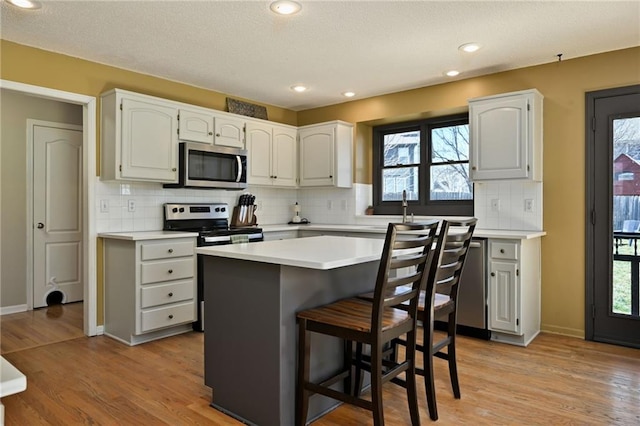 kitchen featuring light wood-style flooring, a kitchen breakfast bar, stainless steel appliances, and light countertops