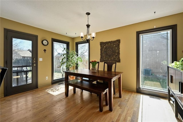 dining room featuring a notable chandelier, light wood-style flooring, baseboards, and visible vents