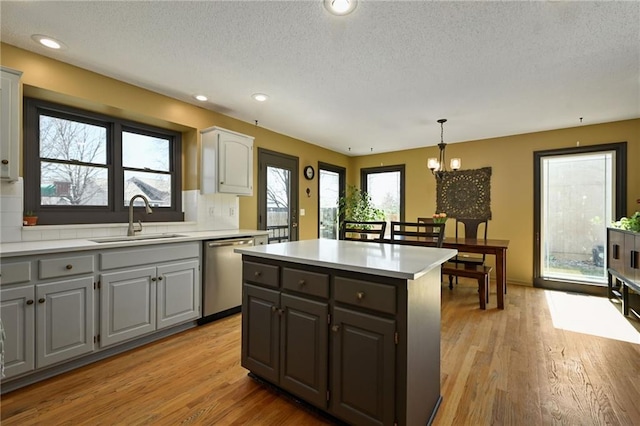 kitchen with light wood-style flooring, gray cabinets, a sink, light countertops, and stainless steel dishwasher