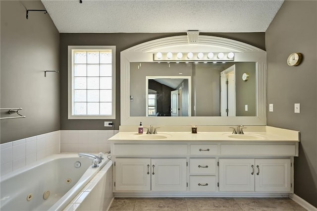 full bath featuring a sink, a textured ceiling, a jetted tub, and double vanity