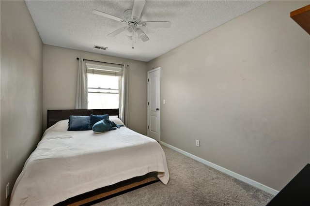 bedroom with a ceiling fan, baseboards, visible vents, carpet floors, and a textured ceiling