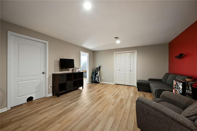 living room featuring visible vents, baseboards, and light wood finished floors