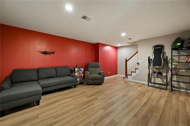 living area with wood finished floors, visible vents, baseboards, recessed lighting, and stairs