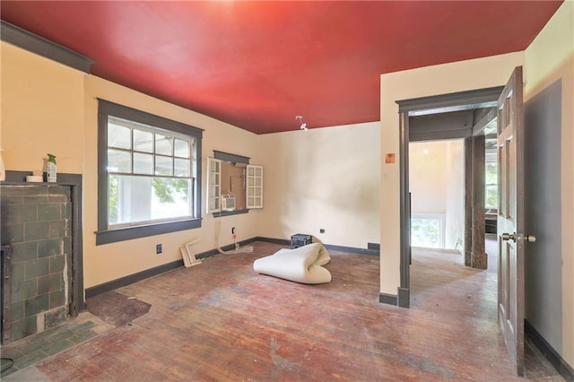 interior space with baseboards, a fireplace with flush hearth, and wood finished floors