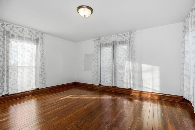 empty room featuring baseboards and wood-type flooring