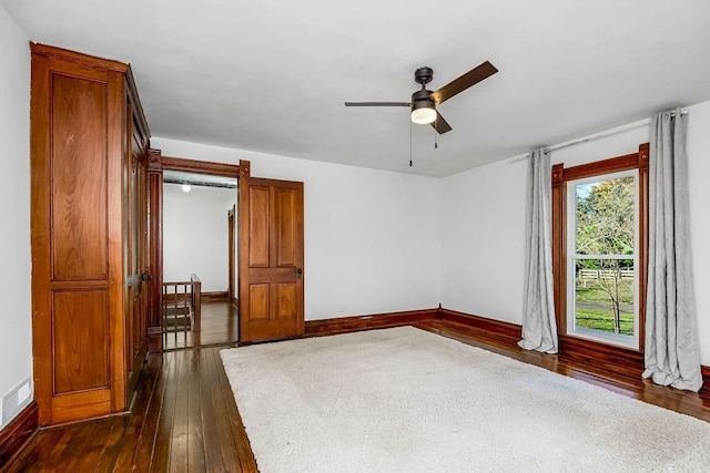 spare room featuring a ceiling fan, visible vents, dark wood-style floors, and baseboards