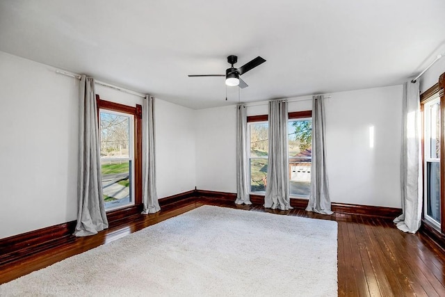 unfurnished room with baseboards, plenty of natural light, and dark wood-type flooring