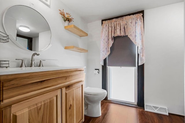 bathroom featuring visible vents, toilet, wood finished floors, and vanity