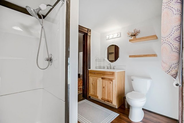 bathroom with toilet, vanity, walk in shower, and wood finished floors