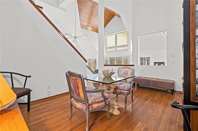 dining area featuring stairway, wood finished floors, baseboards, and high vaulted ceiling