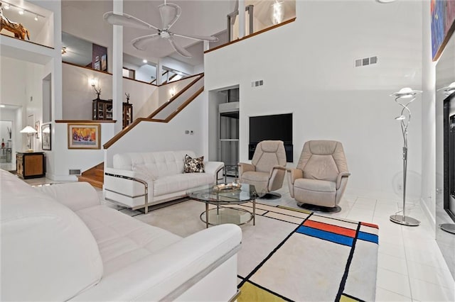 tiled living room featuring stairs, a high ceiling, and visible vents