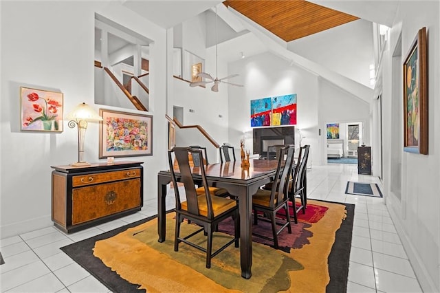 dining space featuring baseboards, stairs, tile patterned floors, high vaulted ceiling, and a ceiling fan